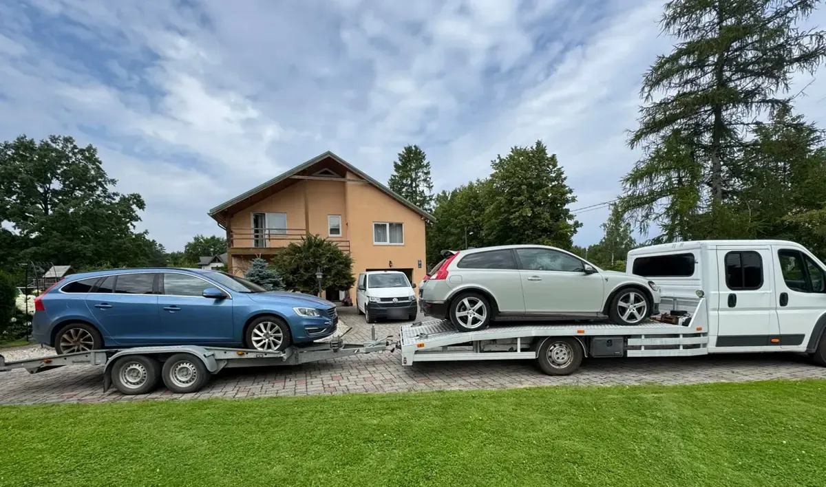 Evakuators ar auto treileri pārvadā divas automašīnas